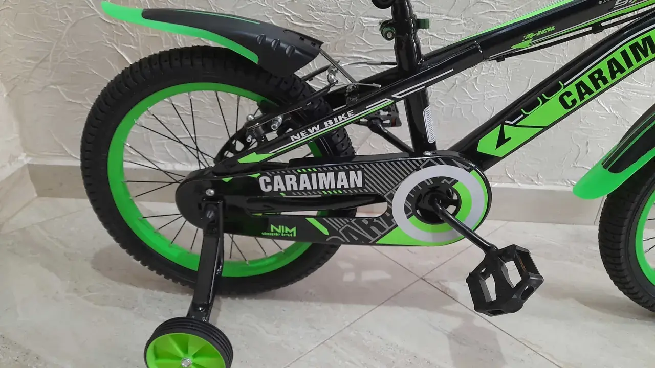 Czarny rower dziecięcy z zielonymi akcentami i napisem "CARAIMAN". To świetny rower dla początkujących.