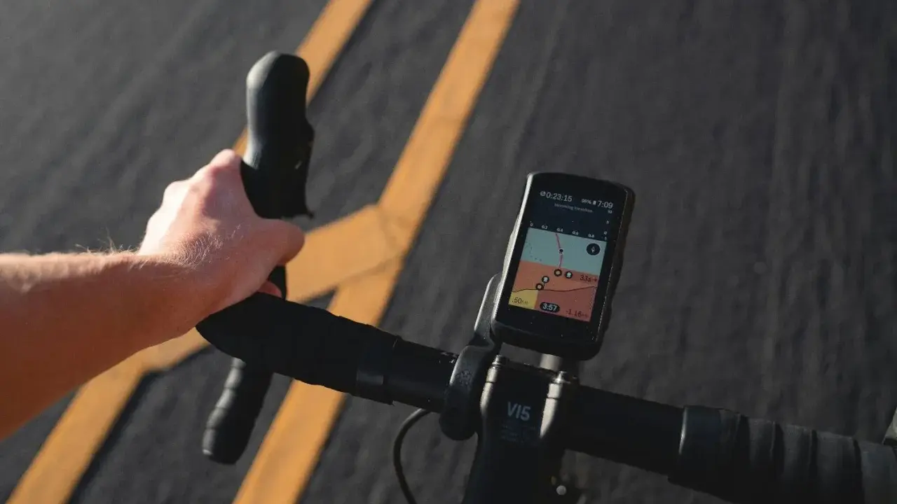 Rowerzysta trzyma kierownicę, na której zamontowana jest aplikacja na rower iPhone z mapą i danymi o trasie.