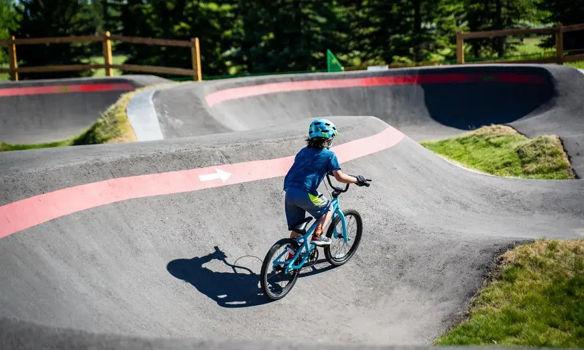 Chłopiec na rowerze pokonuje zakręty na pumptracku, ciesząc się jazdą po falistym torze.