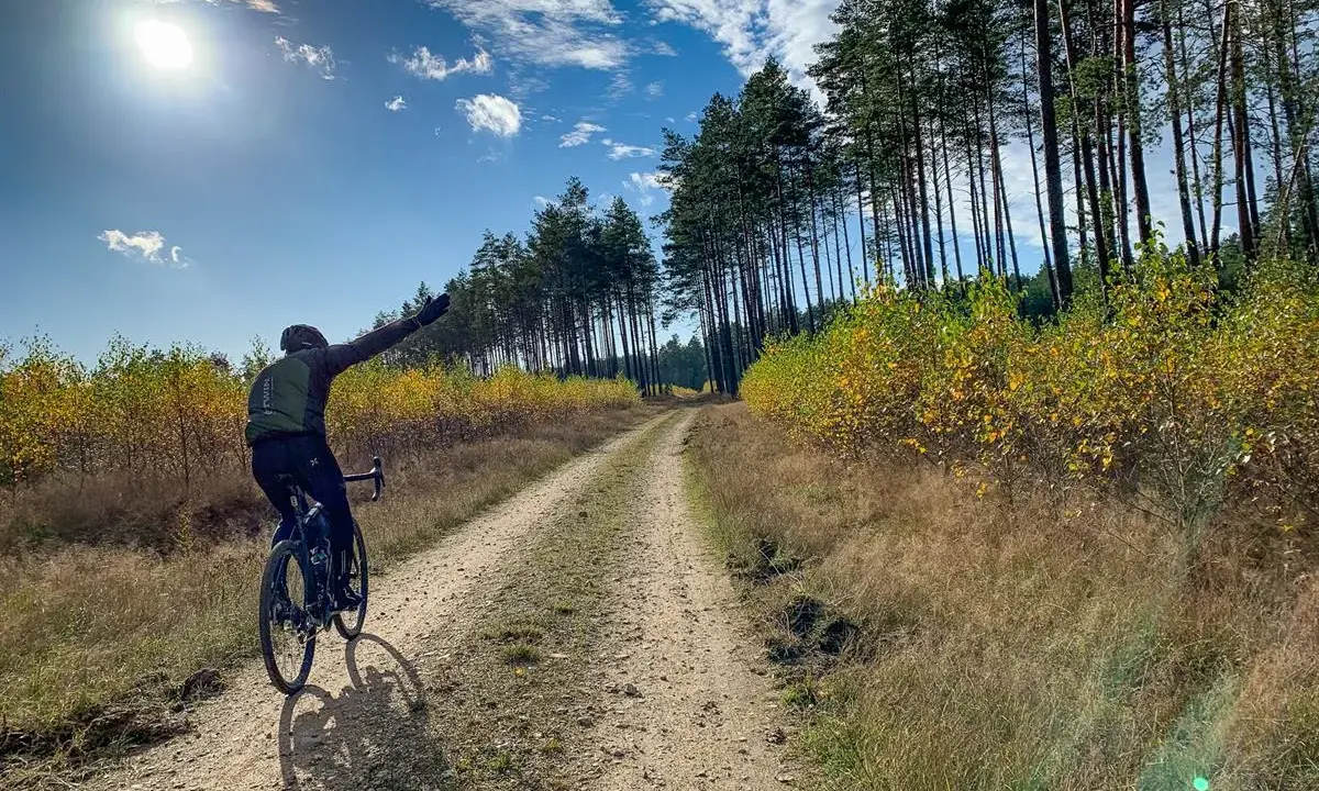 Rowerzysta na szutrowej drodze, cieszący się jesiennym krajobrazem. To prawdziwy gravel po łódzku, z dala od miejskiego zgiełku.