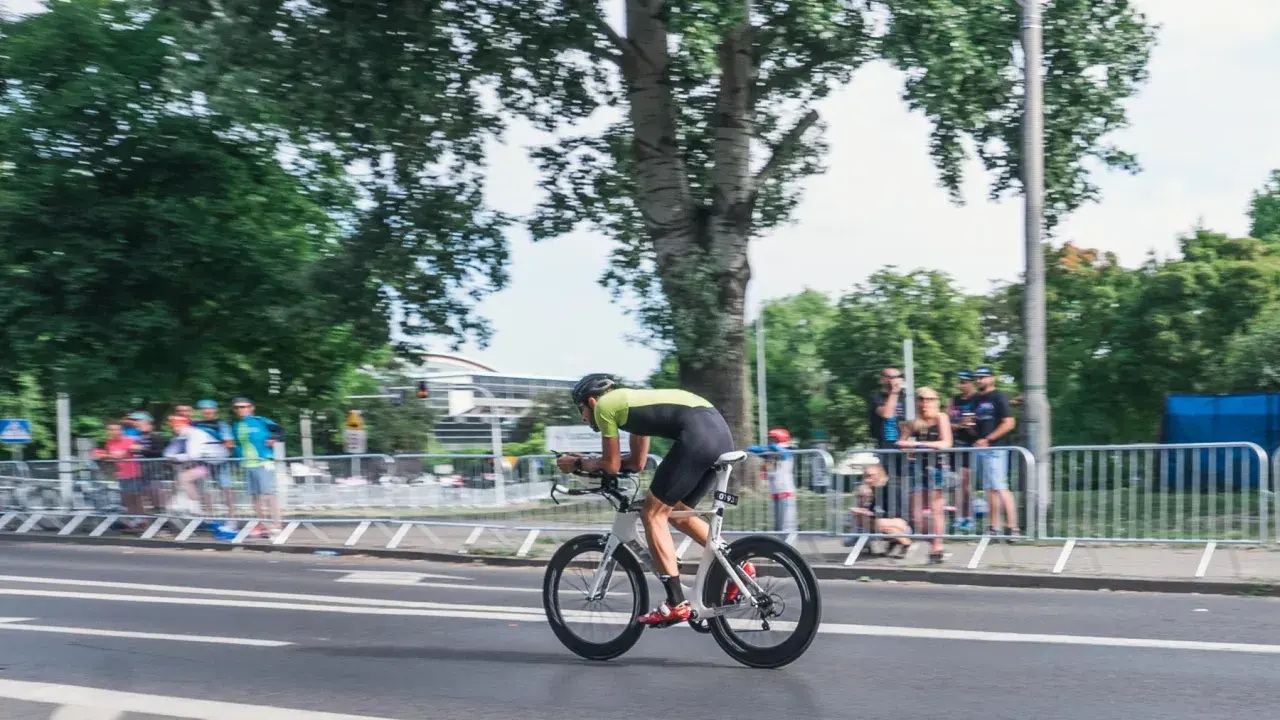 Kolarz w stroju sportowym ściga się na rowerze aerodynamicznym. Myślę, jak sprzedać rower, gdy widzę takie osiągi.