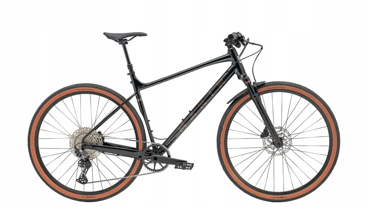 Czarny rower gravel z prostą kierownicą, brązowymi oponami i błotnikami. Idealny na przygody po szutrowych drogach.