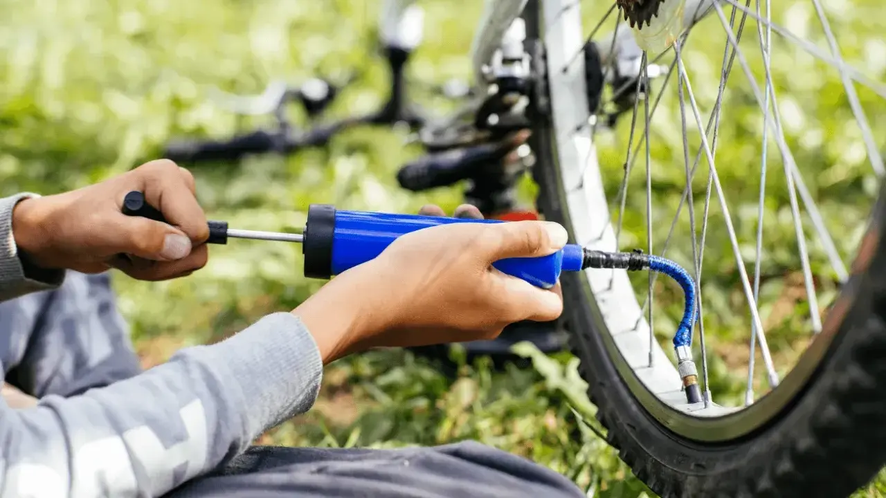 Ręce pompują rowerową oponę przez wentyl schrader.