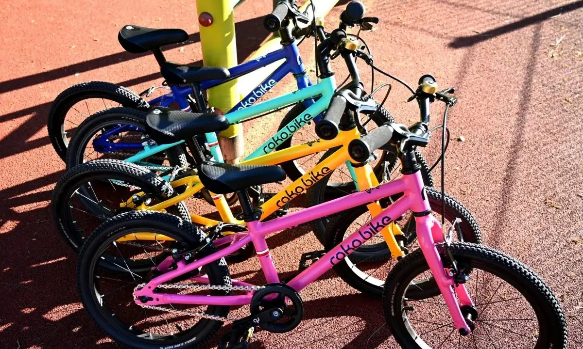 Rowerki dziecięce roko bikes w kolorach: różowym, żółtym, turkusowym i niebieskim, gotowe do zabawy na placu.