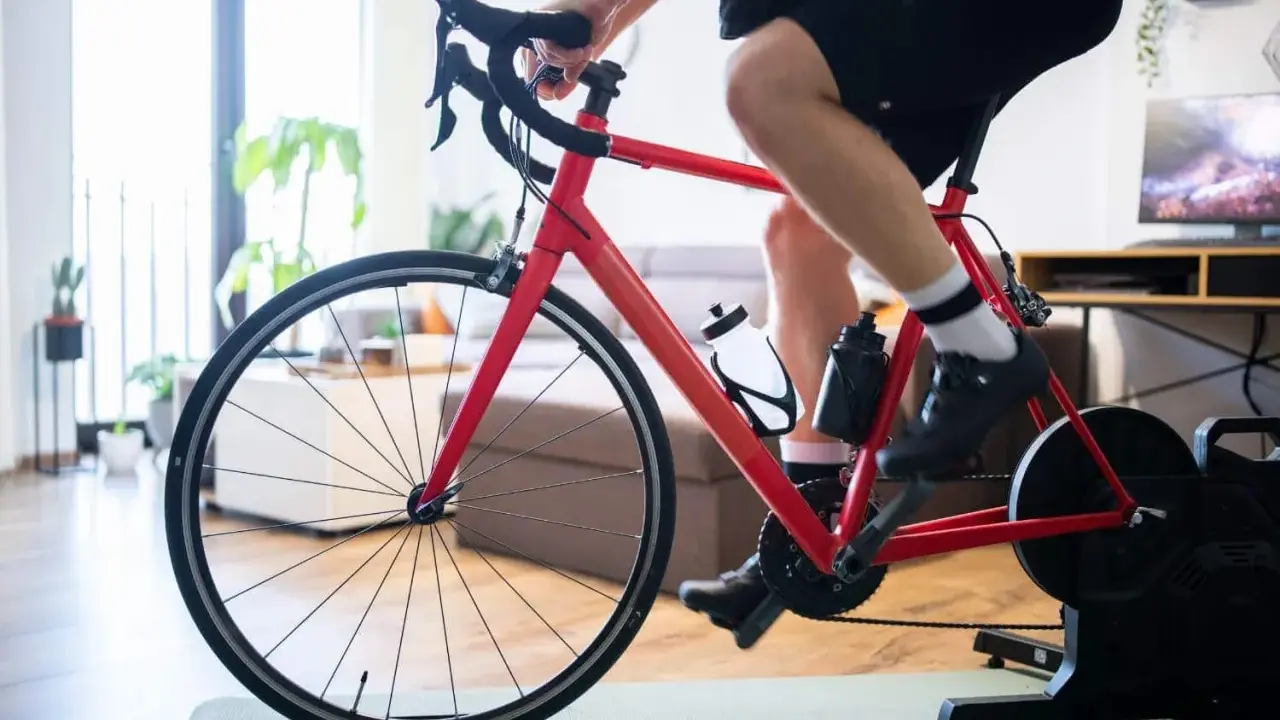 Mężczyzna trenuje na rowerze stacjonarnym z napędem Zwift Hub w domu.