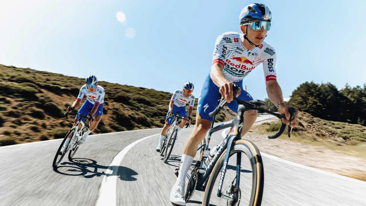 Kolarze jadący w peletonie, pokonując kolejne kilometry Tour de France. Słońce i błękitne niebo towarzyszą im w wyścigu.