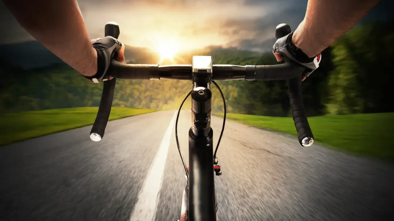 Rowerzysta w rękawiczkach mija pola i lasy, celując w zachód słońca. Dziś na liczniku pojawi się 100 km na rowerze.