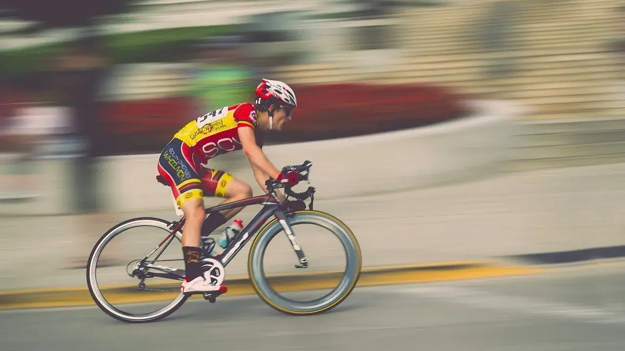 Kolarz w żółto-czerwonym stroju pędzi na rowerze, pokonując kolejny etap ultramaratonu rowerowego.