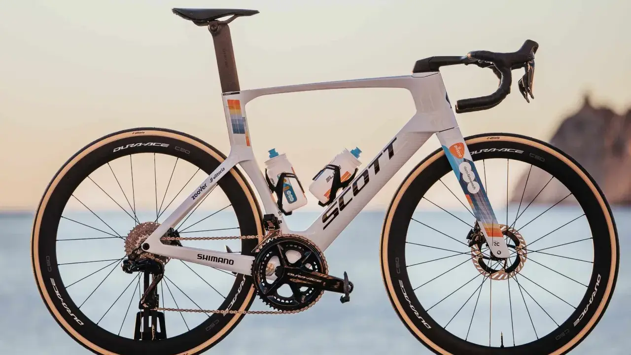 Biały rower szosowy Scott z kolorowymi akcentami, na jakich rowerach jeżdżą kolarze. Wyposażony w Dura-Ace, Shimano i Vittoria.