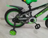 Czarny rower dziecięcy z zielonymi akcentami i napisem "CARAIMAN". To świetny rower dla początkujących.