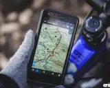 Rękawiczka trzyma smartfon z mapą górską, pokazującą darmowa aplikacja na rower. Idealna do nawigacji w terenie.