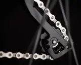 Zbliżenie na mechanizm przerzutki z łańcuchem rowerowym. Widać ogniwa i rolki, kluczowe dla łańcuch rowerowy wymiary.