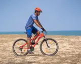 Mężczyzna w kasku jedzie na rowerze po plaży. Sprawdź, co obejmuje gwarancja roweru, by mieć pewność podczas każdej wyprawy.