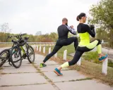 Para ćwiczy na świeżym powietrzu, przygotowując się do treningu w strefie tętna VO2max. Obok stoją rowery.