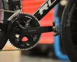 Szukasz informacji, jak dobrać korbę do roweru? Zobacz zbliżenie na czarną korbę Shimano 105 z łańcuchem i pedałem.