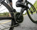 Rowerzysta w butach kolarskich pedałuje, utrzymując optymalną **strefę aerobową** na krętej drodze.