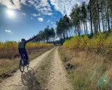 Rowerzysta na szutrowej drodze, cieszący się jesiennym krajobrazem. To prawdziwy gravel po łódzku, z dala od miejskiego zgiełku.