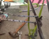 Narzędzia do naprawy roweru, w tym młotek i klucz, leżą obok rozpiętego łańcucha. Dowiedz się, jak rozpiąć łańcuch rowerowy bez spinki.