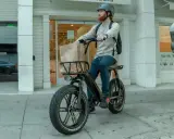 Mężczyzna na rowerze elektrycznym z torbami na zakupy jedzie po chodniku, zastanawiając się, czy można jeździć rowerem po chodniku.