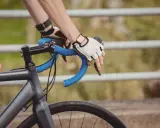 Rowerzysta w rękawiczkach trzyma kierownicę. Czas przekroczyć prog mleczanowy i przyspieszyć.