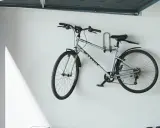 Srebrny rower zawieszony na ścianie za pomocą uchwytu. Praktyczny sposób, jak powiesić rower na ścianie, oszczędzając miejsce.