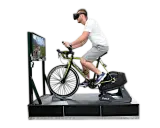 Mężczyzna w goglach VR pedałuje na rowerze stacjonarnym, doświadczając wirtualnej przejażdżki. To zaawansowany symulator jazdy rowerem.