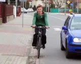 Młody mężczyzna na rowerze jedzie po chodniku, obok drogi. To miejsce, gdzie można jeździć bez karty rowerowej.