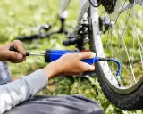 Ręce pompują rowerową oponę przez wentyl schrader.