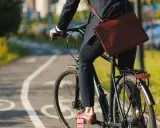 Biznesmen na rowerze z teczką na ramieniu, jadący po ścieżce rowerowej. Czyżby to był zakaz jazdy rowerem w tym miejscu?