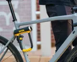 Solidne, żółto-czarne zapięcie rowerowe OnGuard zabezpiecza ramę szarego roweru. To idealne jakie zapięcie do roweru dla każdego rowerzysty.