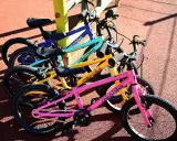 Rowerki dziecięce roko bikes w kolorach: różowym, żółtym, turkusowym i niebieskim, gotowe do zabawy na placu.