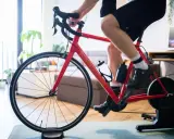 Mężczyzna trenuje na rowerze stacjonarnym z napędem Zwift Hub w domu.