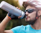 Kolarz w okularach przeciwsłonecznych pije wodę z bidonu. Dobre okulary na rower to podstawa!