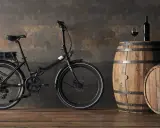 Czarny rower elektryczny, jeden z szwajcarskich marek rowerów, obok drewnianych beczek z winem.