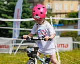 Dziewczynka w różowym kasku na rowerze, z numerem 30. Czy kask na rower dla dziecka jest obowiązkowy? Tak, dla bezpieczeństwa!
