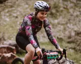 Uśmiechnięta rowerzystka w kwiecistej bluzie pokonuje kolejne kilometry. Dziś cel to 50 km na rowerze po górskich ścieżkach.