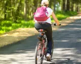 Osoba na rowerze z różowym plecakiem jedzie leśną drogą. Dziś plan to 30 km na rowerze, by nacieszyć się przyrodą.
