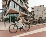 Uśmiechnięta kobieta na rowerze elektrycznym, pokazująca, jak jeździć rowerem elektrycznym, w mieście.