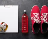 Tabela węglowodanów w produktach, miarka krawiecka, czerwony napój izotoniczny i buty sportowe.