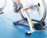 Trenażer rowerowy pozwala ćwiczyć jazdę na rowerze w domu. Widoczny rower jest zamontowany na urządzeniu, które symuluje jazdę.