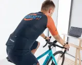 Mężczyzna na rowerze stacjonarnym, korzystający z aplikacji do trenażera na laptopie.