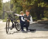 Tata pokazuje synowi, jak działa pierwszy rower dla dziecka. Jesienna sceneria parku.