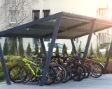 Zadaszona rowerownia w bloku, pełna rowerów gotowych do jazdy.