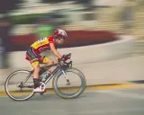 Kolarz w żółto-czerwonym stroju pędzi na rowerze, pokonując kolejny etap ultramaratonu rowerowego.