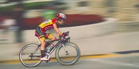 Kolarz w żółto-czerwonym stroju pędzi na rowerze, pokonując kolejny etap ultramaratonu rowerowego.