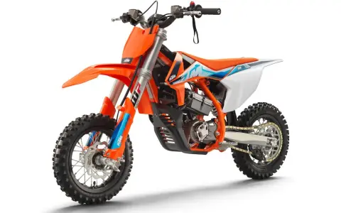 Pomarańczowy motocykl KTM SX-E 5, idealny dla młodych adeptów motocrossu. To świetny sposób, by zacząć przygodę z tym sportem i poznać, co to KTM.