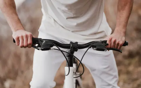 Dłonie na kierownicy roweru szosowego. Zastanawiasz się, jak dobrać szerokość kierownicy szosowej?