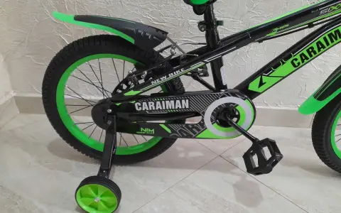 Czarny rower dziecięcy z zielonymi akcentami i napisem "CARAIMAN". To świetny rower dla początkujących.