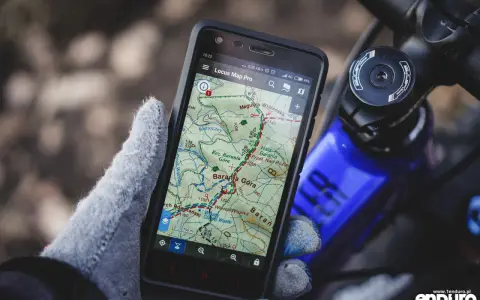 Rękawiczka trzyma smartfon z mapą górską, pokazującą darmowa aplikacja na rower. Idealna do nawigacji w terenie.