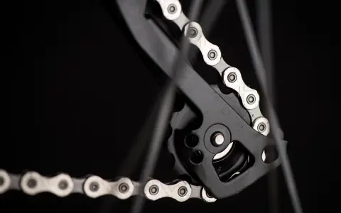 Zbliżenie na mechanizm przerzutki z łańcuchem rowerowym. Widać ogniwa i rolki, kluczowe dla łańcuch rowerowy wymiary.